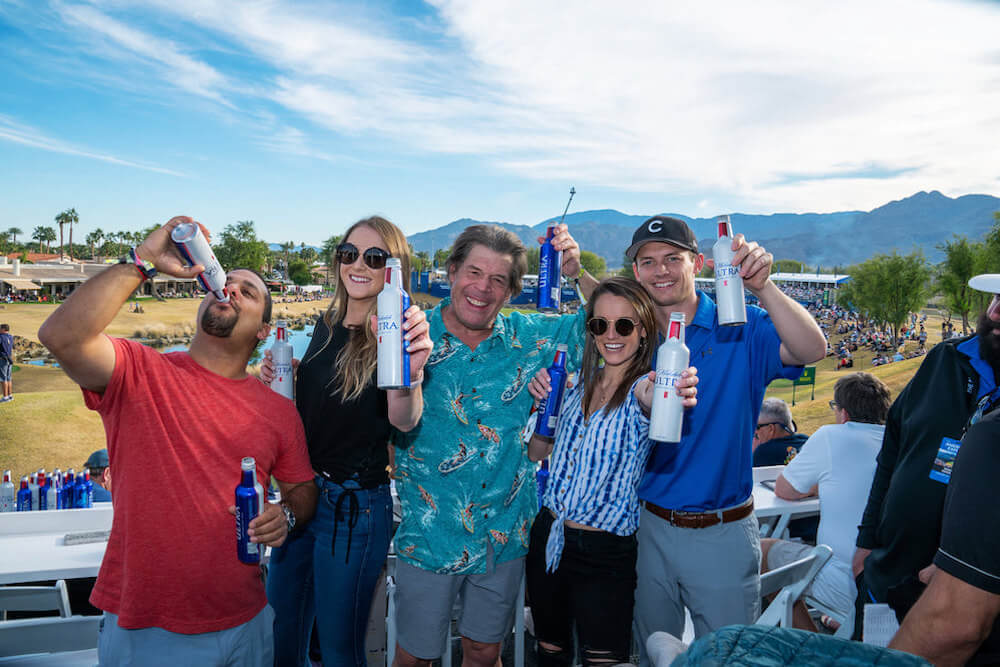 people holding beers and smiling in front of golf course
