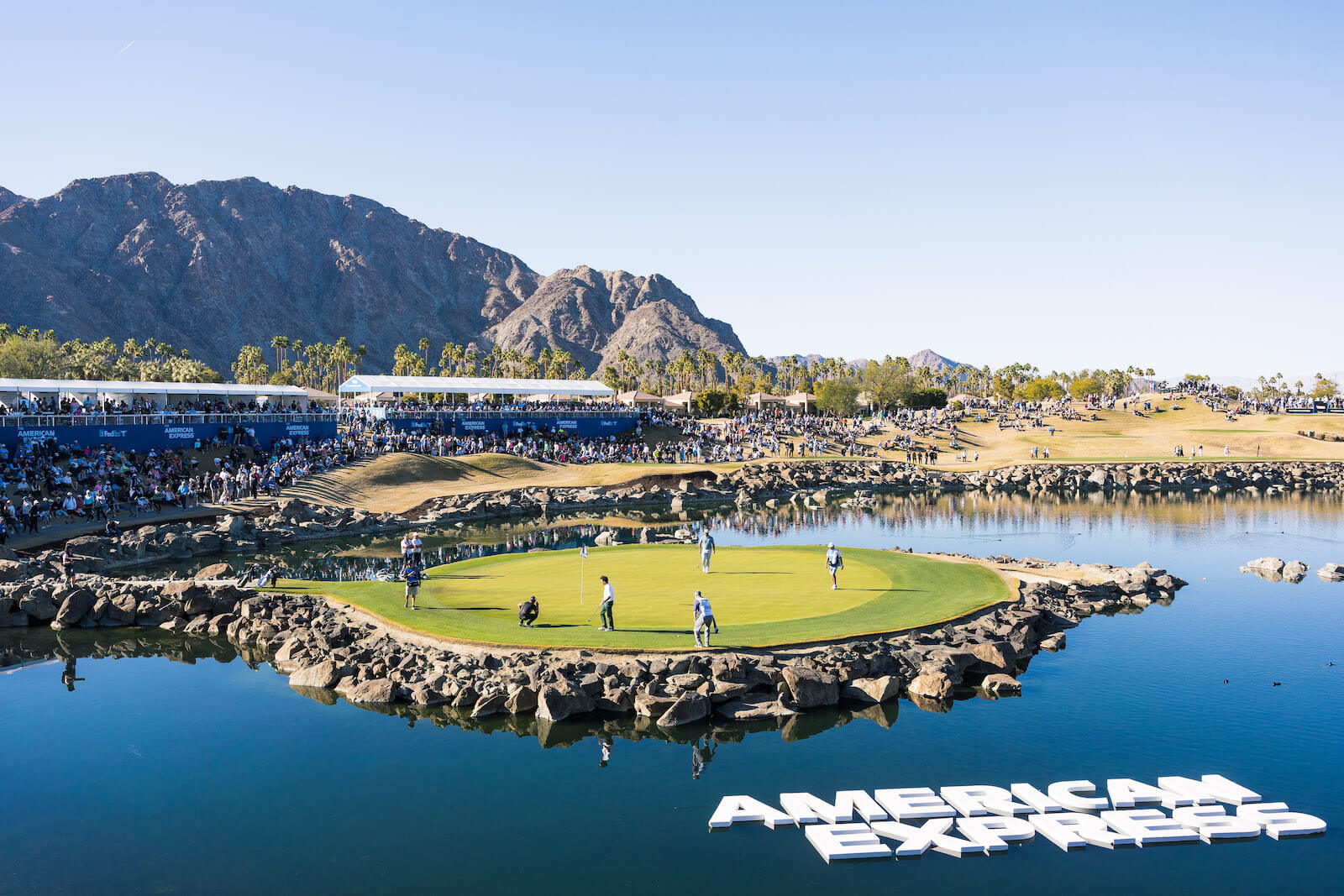 american express letters on a pond in middle of gold course surrounded by mountains